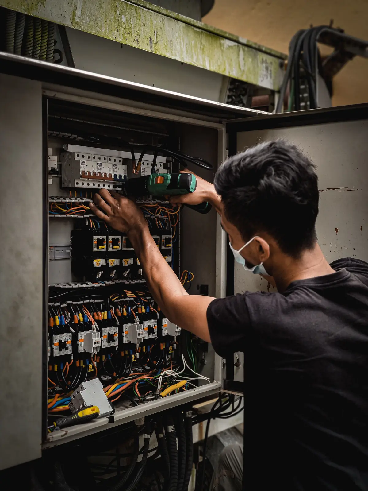 An electrician working inside a large distribution board, for commercial electrical in Toronto