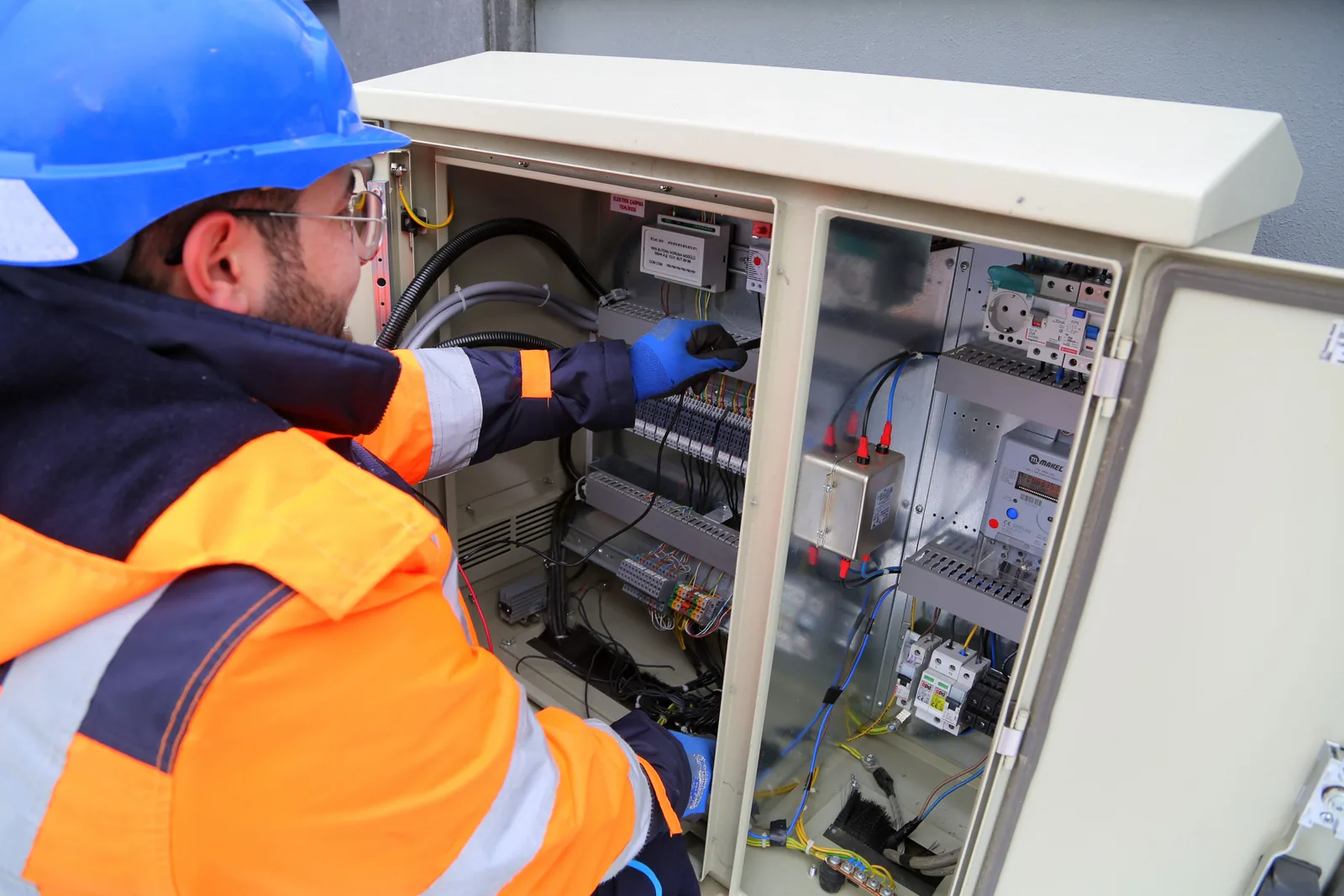 An electrician working in an outdoor service cabinet, for maintenance plans in Toronto